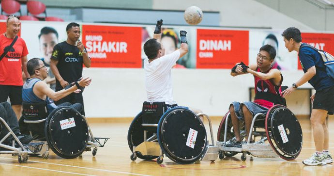 Participants at a wheelchair rugby workshop practice passing balls between themselves