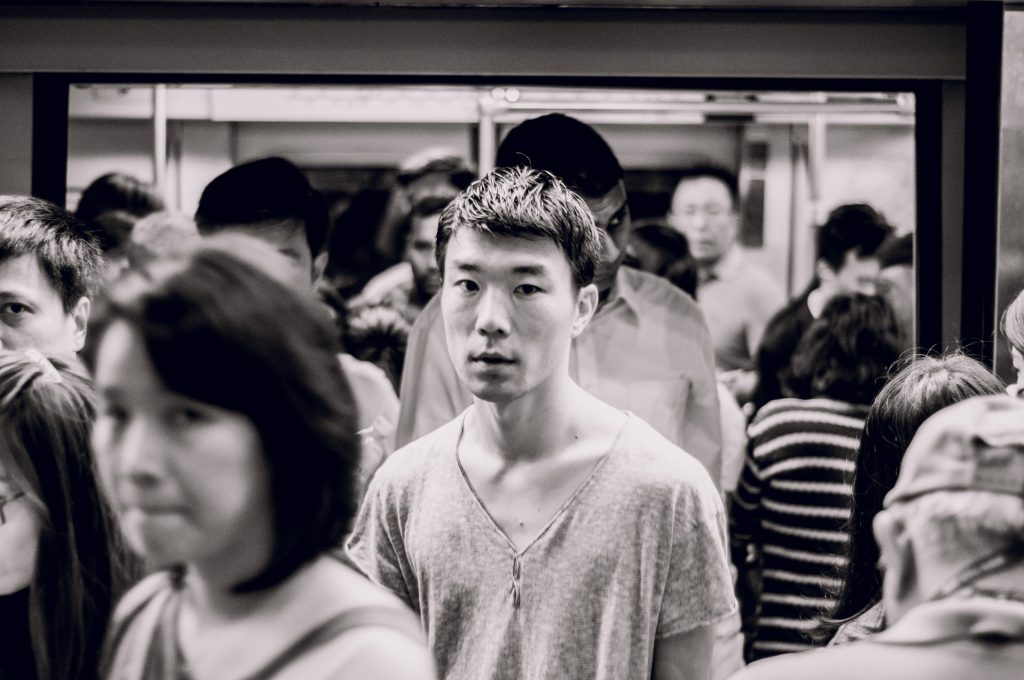 Black and white photograph of passengers alighting from an MRT train. Some of them are looking straight at the photographer.