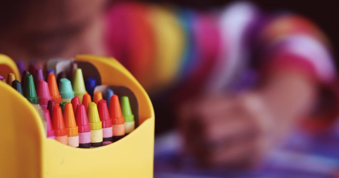 Photo of a child with a box of colourful crayons