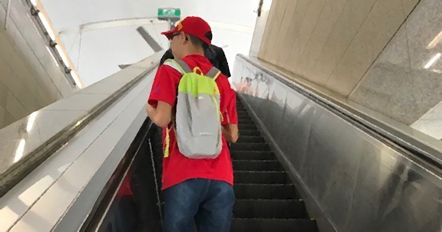 Photo of an independent travelling project participant riding an escalator at an MRT station