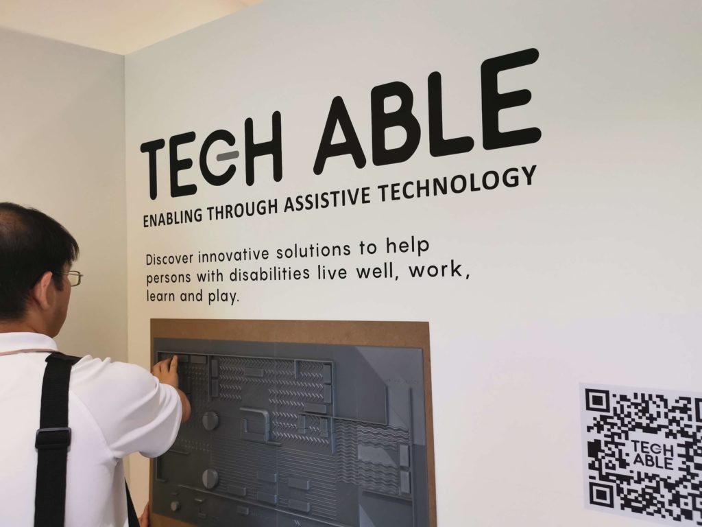 Visitor using the tactile map which features Braille and three-dimensional structures at one of the entrances of Tech Able.