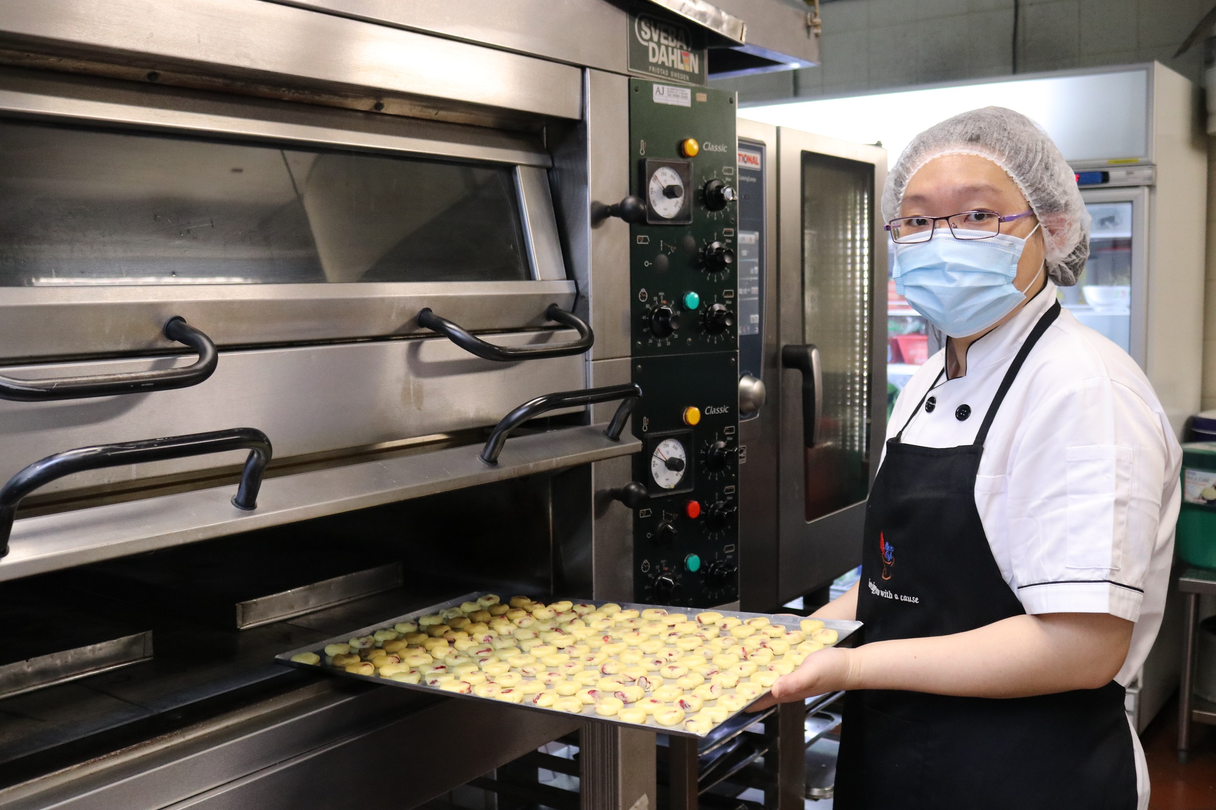 Shirley Heng from Metta Cafe posing with a plate of pastries to be baked in the kitchen
