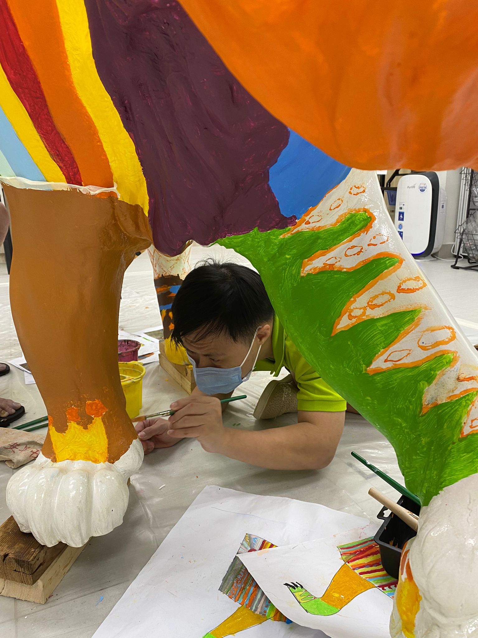 TOUCH artist crouching down to paint the paw part of the tiger sculpture.