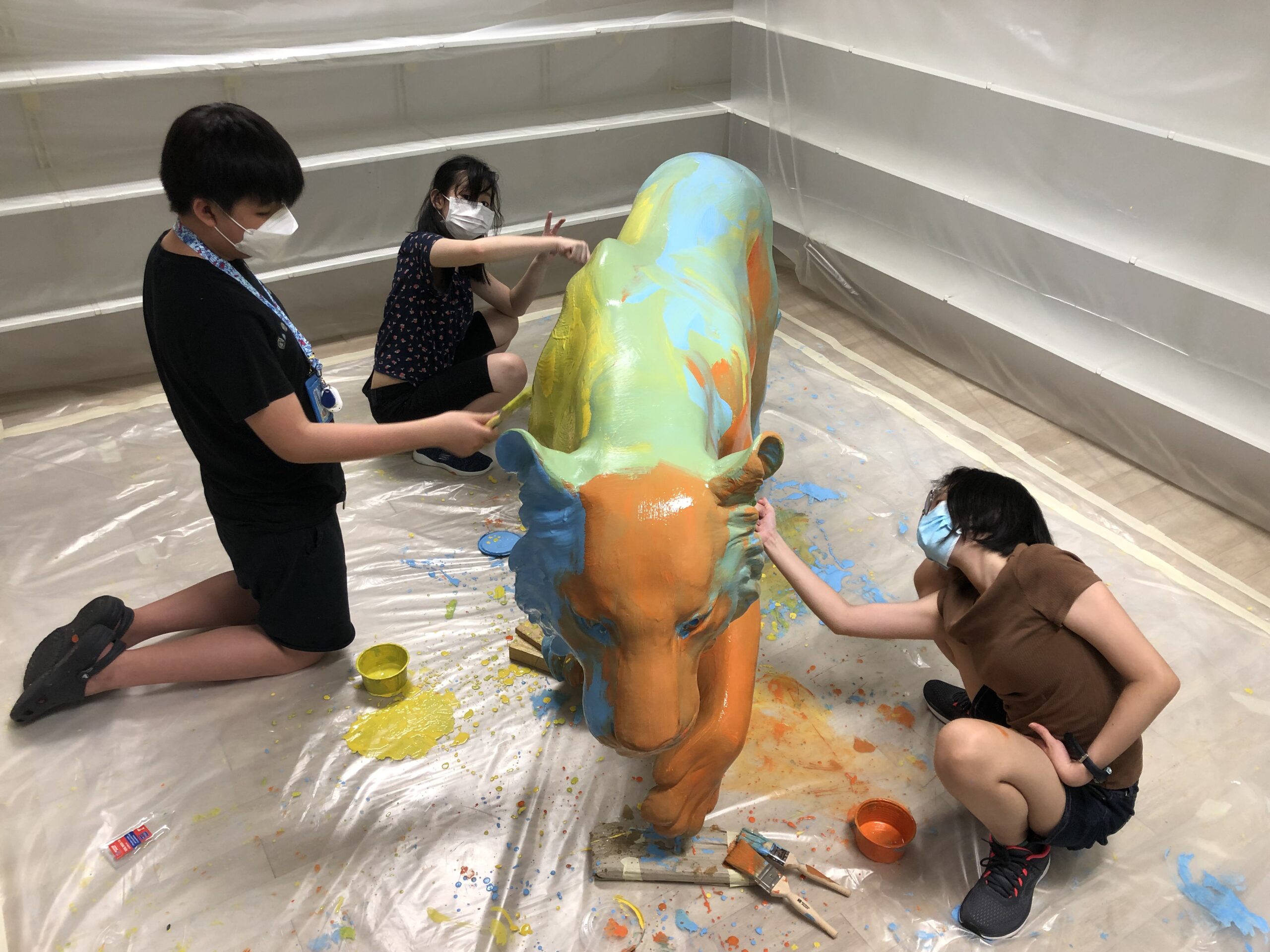 The Art Faculty artists painting the first layer of paint on their tiger sculpture