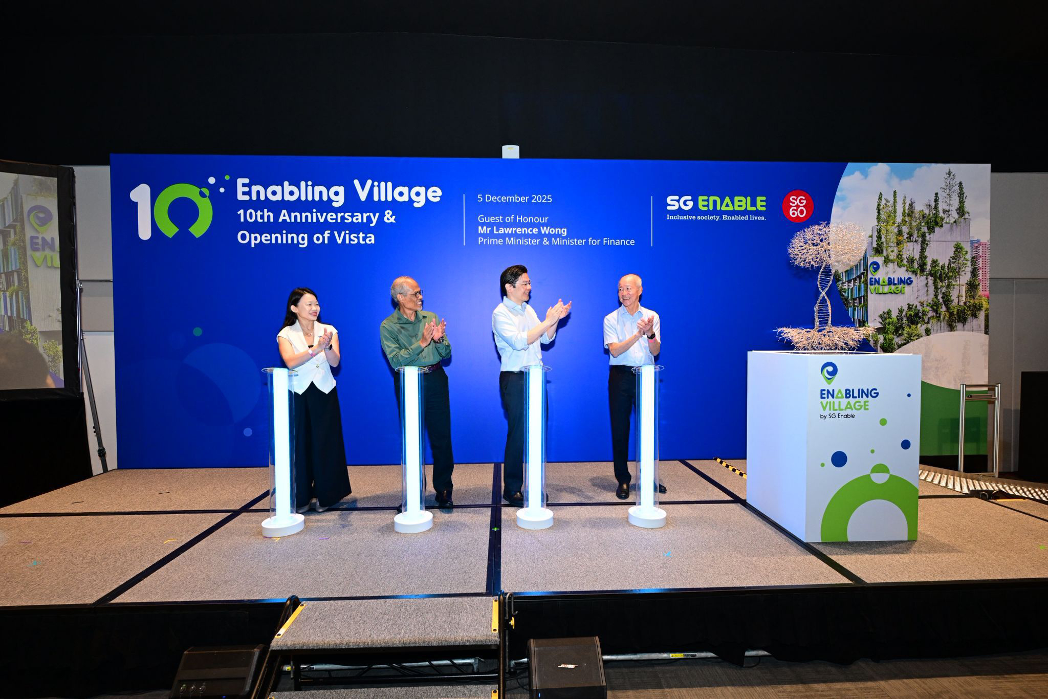 a photo of Mr Lawrence Wong, Prime Minister and Minister for Finance on stage clapping in front of Enabling Village 10th anniversary unveiling Victor's work