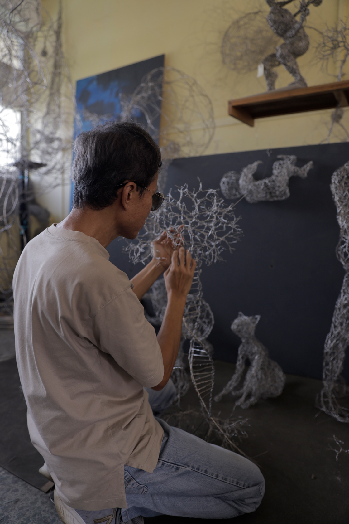 a candid photo of victor tan working on his sculpture in his workshop from the back